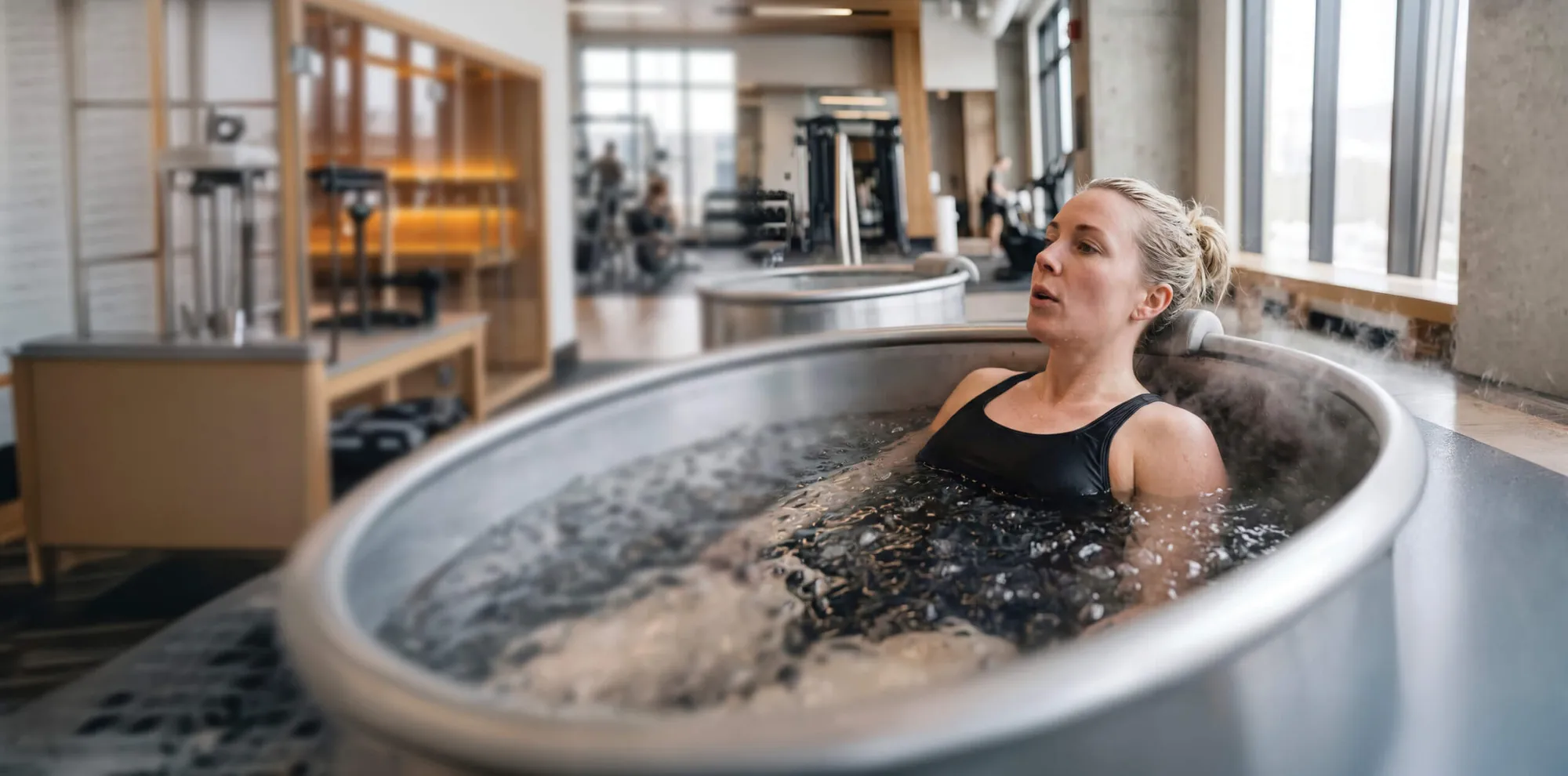 Woman sitting in a stainless steel ice bath filled with ice